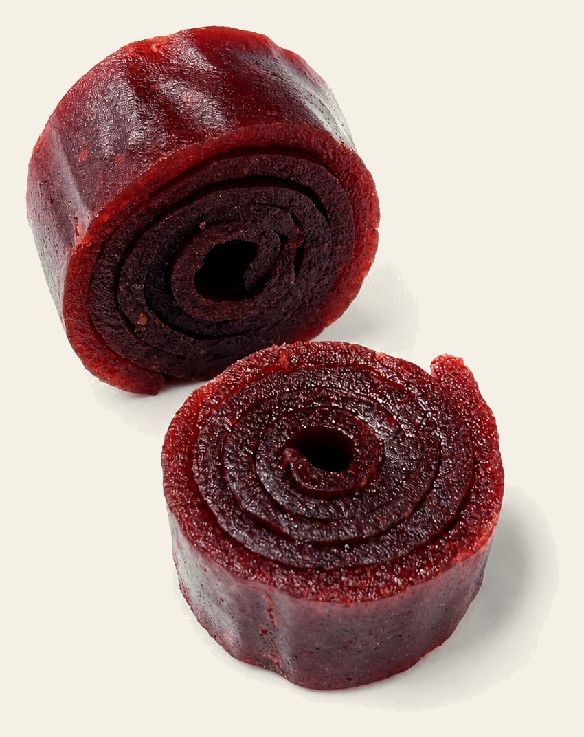 Fruit purée roll-ups, one standing and one cut to show the coil